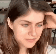 a close up of a woman 's face with her hand on her hair .