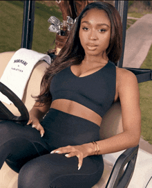 a woman sitting in a golf cart with a towel that says womani athletics