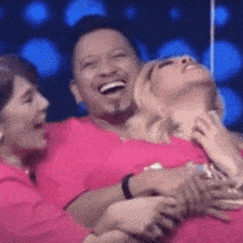 a man and two women are hugging and laughing