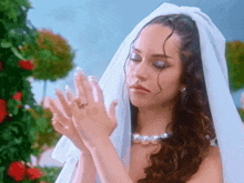 a woman in a wedding dress with a veil and pearls on her necklace