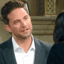 a man in a suit is talking to a woman in a black shirt