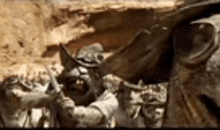 a close up of a statue of a man holding a sword in front of a rock .