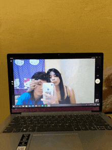 a laptop screen shows a couple taking a selfie