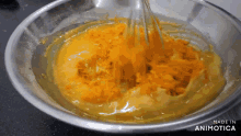 a bowl of yellow liquid is being whisked by a whisk and the words made in animotica are on the bottom