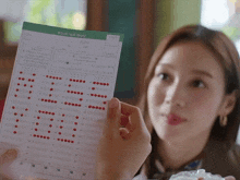 a woman is holding a piece of paper that says ' a ' on the top of it