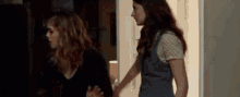 a couple of women standing next to each other in a dark room .