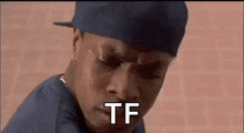 a man wearing a hat and a blue shirt is making a funny face .