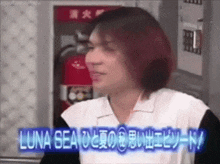 a man with red hair is standing in front of a fire extinguisher and a sign that says luna sea on it .