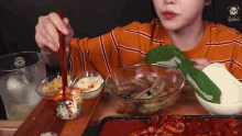 a person eating a bowl of food with chopsticks and a skull on their shirt