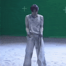 a man is standing in front of a green screen with a cross in the middle