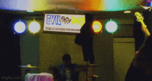 a man playing drums in front of a sign that says evil finds kid