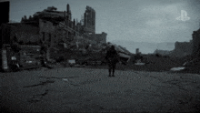 a black and white photo of a person walking down a road in front of a destroyed city .