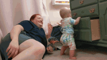 a woman and a baby are playing with a dresser