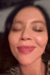 a close up of a woman 's face with her eyes closed and her tongue out .