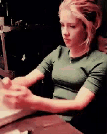 a woman in a green shirt is sitting at a table using a laptop computer .