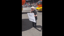an elderly woman holds a sign that says nice wiener