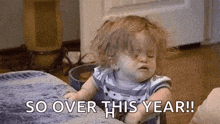 a baby girl is sitting on a bed and making a funny face while saying `` so over this year ! ''