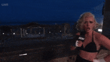 a woman in a bikini is holding a microphone that says aew on it