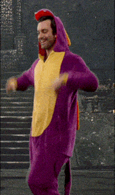 a man in a purple and yellow dinosaur costume