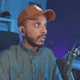 a man wearing a hat and headphones is sitting in front of a microphone .