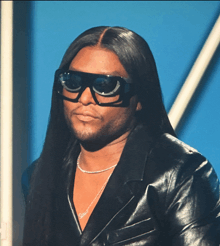 a man with long hair wearing sunglasses and a name necklace that says steur