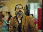 a man with a beard is standing in front of a sign that says ' kevserpayasi ' on it