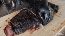 a large piece of meat is being sliced on a cutting board with the words made in animotica visible