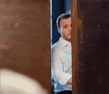 a man in a white shirt is standing in a doorway .
