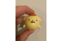 a person is holding a small yellow figurine with a brown hat on top