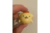 a person is holding a small yellow figurine with a brown hat on top