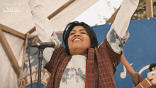 a woman singing into a microphone with her arms in the air in front of a sign that says son of a glitch