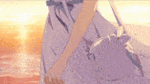 a girl in a purple dress is holding a white purse while walking on the beach .
