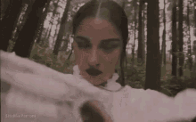 a woman is standing in the middle of a forest holding a piece of paper .