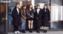 a group of girls standing in front of a building that says dispatch