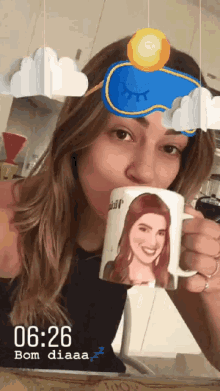 a woman wearing a sleep mask is drinking from a mug that says bom diaaa