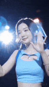 a woman in a blue tank top is waving her hand