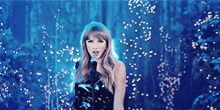 a woman in a black dress is singing into a microphone in a dark forest .