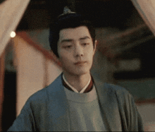 a man wearing a kimono and a crown is standing in front of a curtain .