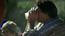 a man in a plaid shirt is holding a glass of orange juice