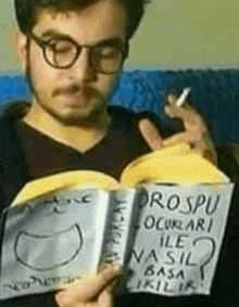 a man is reading a book and smoking a cigarette while holding a sign .