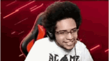 a man wearing glasses and headphones is sitting in a red chair .