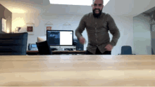 a man with a beard is dancing in front of a computer monitor that says adobe