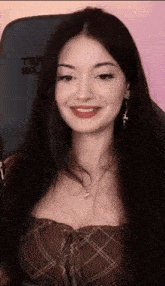 a woman with long dark hair is smiling while sitting in front of a microphone .