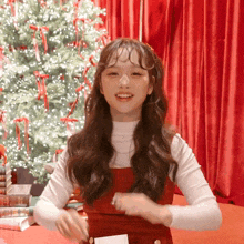 a girl in front of a christmas tree holds a piece of paper