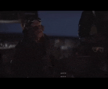 a man with goggles on his head is standing in the dark and says " i bce ckazan "