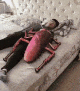 a person is laying on a bed with a cockroach pillow on their stomach .