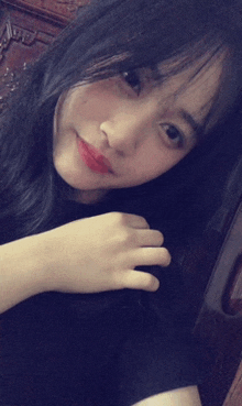 a girl with long black hair is taking a selfie with her hand on her hair