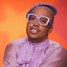 a man wearing a purple shirt and glasses looks at the camera