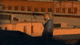 a man in a suit is talking on a cell phone in front of a brick building