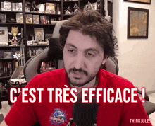 a man in a red shirt says " c'est tres efficace " in front of a microphone